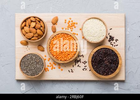 Verschiedene Superfoods in der kleinen Schüssel auf farbigem Hintergrund. Superfood wie Reis, Chia, Quinoa, Linsen, Nüsse, Sesamsamen, Mandeln. Draufsicht. Stockfoto