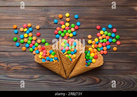 Waffelkonus voller traditioneller Süßigkeiten, die auf farbigen Hintergrund fallen, mit Platz für Kopien. Frohes Weihnachtsangebot. Stockfoto