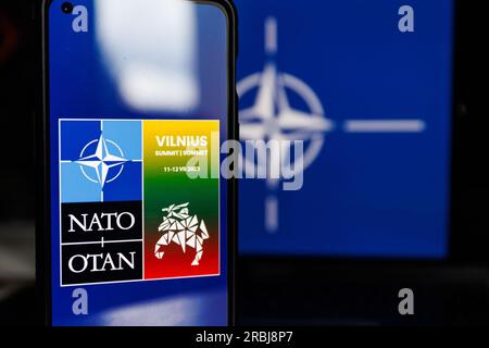 Vilnius, Litauen - 2023. Juli 10: NATO-Gipfel Vilnius Logo auf dem Bildschirm und NATO-Flagge. Hochwertiges Foto Stockfoto
