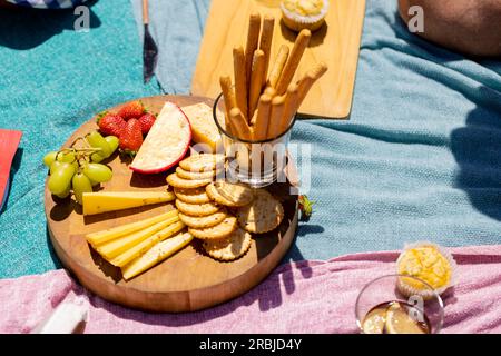 Nahaufnahme von blauen Decken mit Essen auf Schneidebrettern. Picknick, Zeit zur freien Verfügung, Getränke und Speisen, unveränderte Speisen. Stockfoto