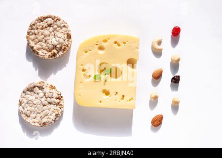 Kreatives gesundes Frühstückskonzept auf einem weißen Hintergrund. Käse, kalziumreiches Essen, Nüsse, getrocknete Früchte, Vollkorn-Knäckebrot, Draufsicht, Kopie Stockfoto