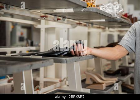 Ein Schuhmacher, der einen Schuh zuletzt in der Fabrik hält Stockfoto