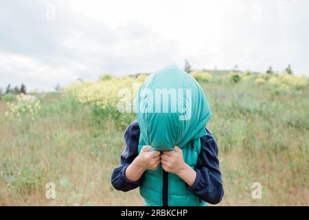 Ein junges Mädchen, das ihre Kapuze über dem Gesicht hält, ist albern Stockfoto