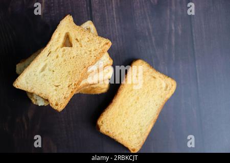 Teezeit-Snack. Gesunder Weizenrusk serviert mit indischem heißen Masala-Tee und Milchkännchen auf schwarzem Hintergrund. Auch bekannt als Mumbai Cutting Chai. Stockfoto