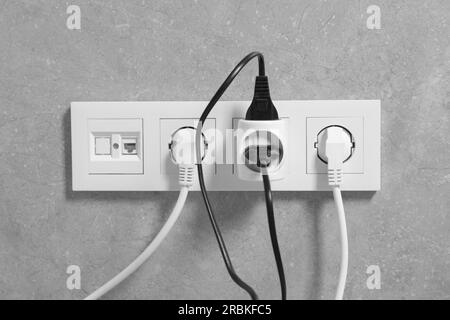 Viele verschiedene elektrische Netzstecker in grauen Wandsteckdosen Stockfoto