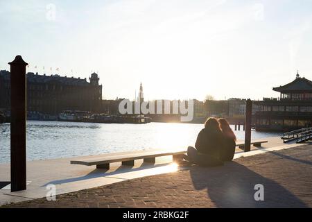 Zwei Freundinnen sitzen zusammen und sehen den Sonnenuntergang in Amsterdam Stockfoto