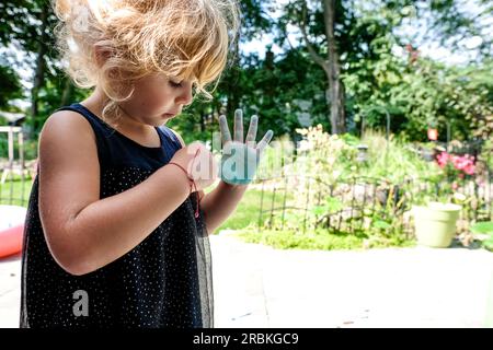 Kleine Mädchen mit Kreide an den Händen im Sonnenlicht Stockfoto