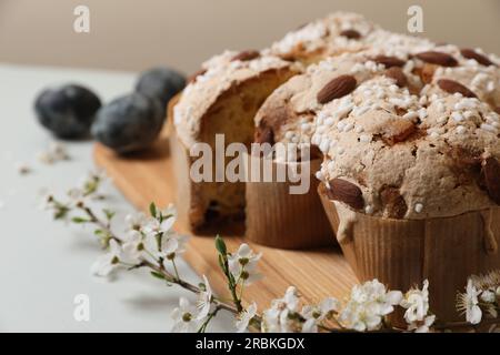 Stücke köstlicher italienischer Ostertaubenkuchen (traditionell Colomba di Pasqua), Zweig mit Blumen und bemalten Eiern auf hellgrauem Tisch, Nahaufnahme Stockfoto