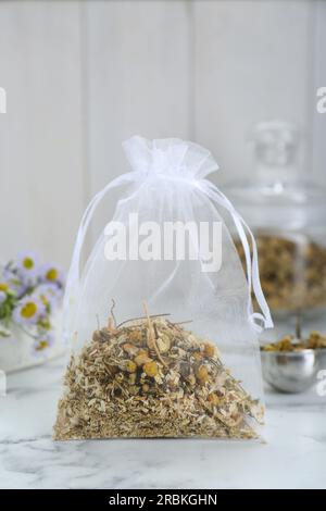 Duftbeutel mit getrockneten Kamillenblumen auf einem weißen Marmortisch Stockfoto