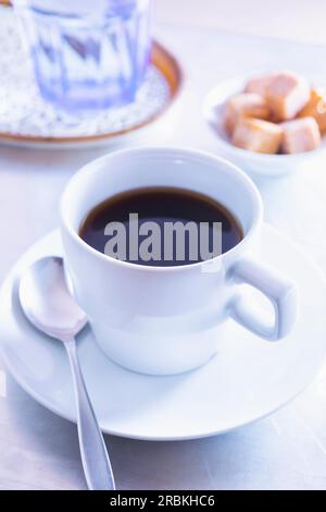 Kaffeetasse, ein Glas Wasser und Zuckerwürfel Stockfoto