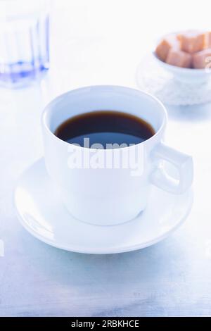 Kaffeetasse, ein Glas Wasser und Zuckerwürfel Stockfoto