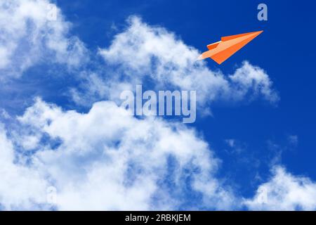 Weiße Wolken und Papierflugzeug fliegen am blauen Himmel an sonnigen Tagen. Platz für Text Stockfoto