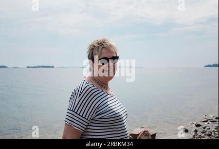 Eine Frau, die am Meer steht und lächelt Stockfoto