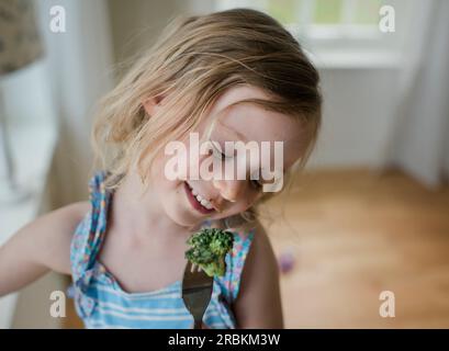 Porträt eines jungen Mädchens, das Brokkoli mit einem schmutzigen Gesicht isst Stockfoto