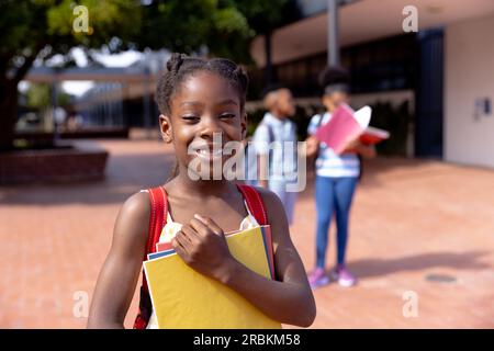 Portrait eines glücklichen afroamerikanischen Schulmädchens, das auf dem Schulhof steht Stockfoto