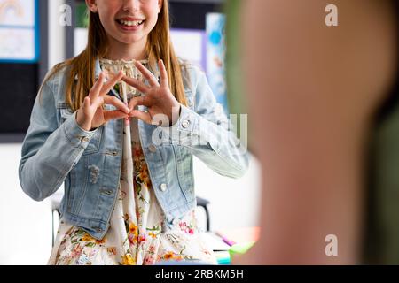 Glückliche, vielfältige Schulkinder, die Gebärdensprache im Schulunterricht benutzen Stockfoto