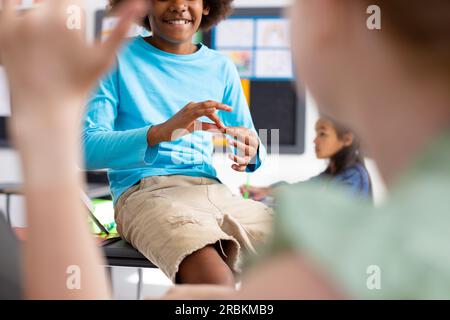 Glückliche, vielfältige Schulkinder, die Gebärdensprache im Schulunterricht benutzen Stockfoto