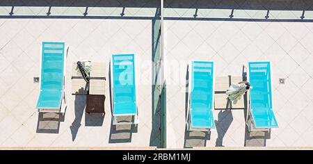 Sonnenliege mit Sonnenschirm und Strandzubehör für aktive Erholung am Pool, Kopierbereich, Draufsicht Stockfoto