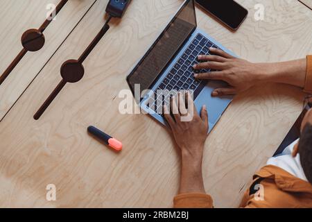 Nahaufnahme der Hände, die Text auf der Laptop-Tastatur am Holztisch eingeben Stockfoto