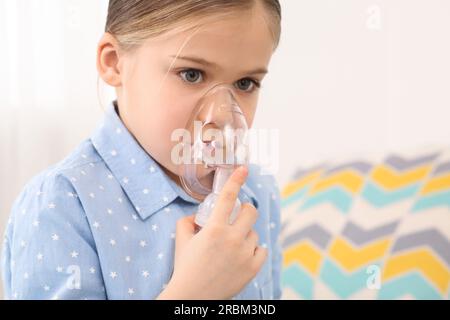 Krankes kleines Mädchen mit Vernebler zur Inhalation in Innenräumen Stockfoto