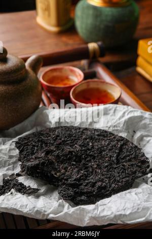 Gebrochener, scheibenförmiger pu-erh-Tee und auf dem Tisch Stockfoto