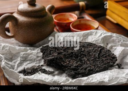 Gebrochener, scheibenförmiger pu-erh-Tee und auf dem Tisch Stockfoto