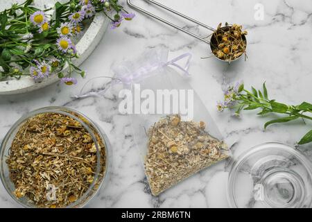 Duftbeutel und getrocknete Kamillenblumen auf weißem Marmortisch, flach liegend Stockfoto