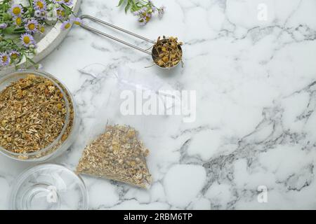 Duftbeutel und getrocknete Kamillenblumen auf weißem Marmortisch, flach liegend. Platz für Text Stockfoto