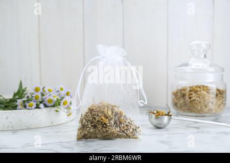 Duftbeutel mit getrockneten Kamillenblumen auf einem weißen Marmortisch Stockfoto