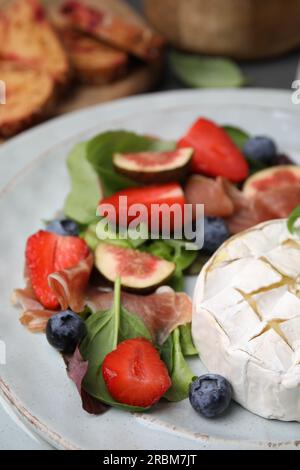 Köstlicher Salat mit Brie-Käse, Blaubeeren, Feigen und Erdbeeren auf dem Teller, Nahaufnahme Stockfoto