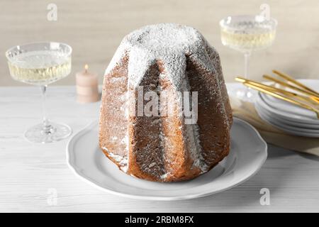 Köstlicher Pandoro-Kuchen mit Puderzucker und Sekt auf einem weißen Holztisch. Traditionelles italienisches Gebäck Stockfoto