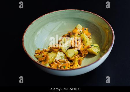 Wilde Pfifferling-Pilze mit gekochten Kartoffeln und Kräutern. Ein köstliches vegetarisches Mittagessen mit saisonalen Zutaten. Stockfoto