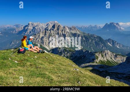 Mann und Frau wandern eine Pause und schauen Castello di Moschesin und Monte Pelmo, Belluneser Höhenweg, Dolomiten, Veneto, Veneto, Italien Stockfoto