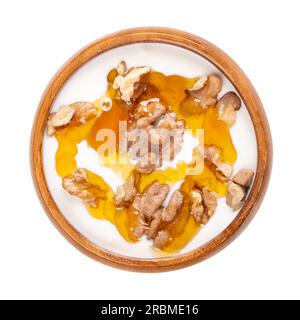 Griechischer Joghurt mit Honig und gerösteten Walnüssen, in einer Holzschüssel. Yiaourti me meli, traditionelle kleine Leckerei, Nachtisch und Snack. Stockfoto