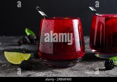 Beere Limonade, erfrischendes Getränk, Cocktail, Eistee, Blackberry und Lime Cold Summer Drink im dunklen Hintergrund Stockfoto