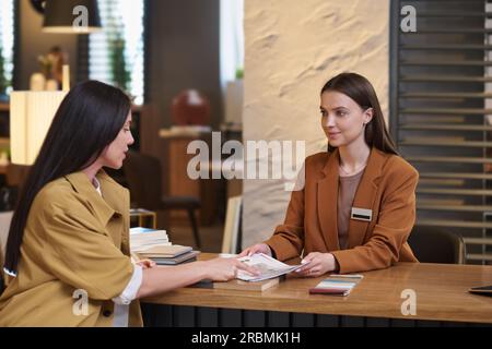 Junge selbstbewusste Frau, die auf eine Skizze zeigt und ihre Details der Innenarchitektin bei einem Termin im Freiraumbüro erklärt Stockfoto