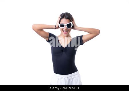 Studioporträt einer jungen braunen Modelin, die eine lustige, schicke, weiße Sonnenbrille trägt und lächelt Stockfoto