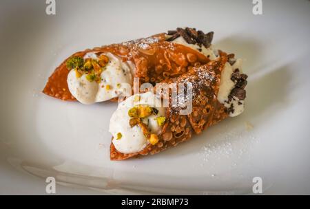 Hausgemachte italienische Cannoli gefüllt mit Ricotta Creme auf weißem Teller. Stockfoto