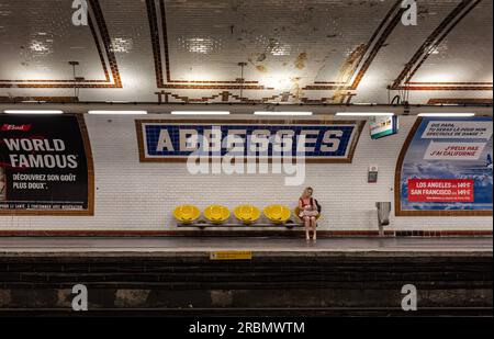 Frau überprüft ihr Handy, während sie auf den Zug in der U-Bahn-Station Abbesses, Linie 12, Montmartre, 18 Arr. Wartet. Paris Stockfoto