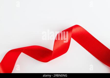 Rotes Seidenband zum Einwickeln von Geschenken auf weißem Hintergrund. Locken aus dekorativem Weihnachtsband. Element für Konstruktion. Stockfoto