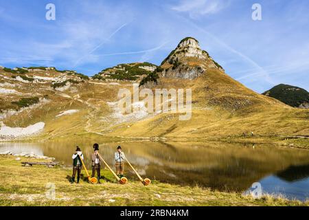 Drei österreichische Alphornmusiker namens „Klangholz“ spielen Alphorn am Augstsee auf dem Mount Loser in Österreich. Stockfoto