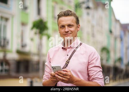 Ein Mann mittleren Alters, der im Freien eine Nachricht schrieb. Mit seinem Mobiltelefon in der Hand nutzt er digitale Kommunikation, um sich mit anderen in der städtischen Umgebung zu vernetzen. Hochwertiges Foto Stockfoto