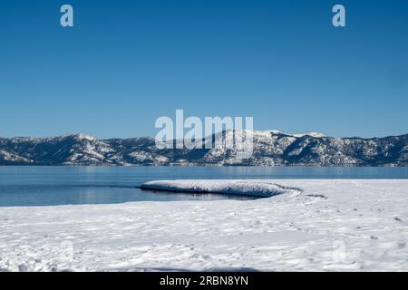 Im Winter am gefrorenen Ufer des Lake Tahoe, mit wolkenlosem blauem Himmel und Wasserkopien, in der Nähe von Tahoe City auf der kalifornischen Seite Stockfoto