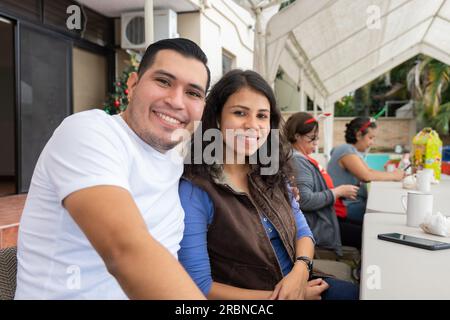 Tegucigalpa, Francisco Morazan, Honduras - 28. November 2022: Fröhlicher junger Brown man and Woman Smile At a Table während einer Weihnachtsfeier Stockfoto