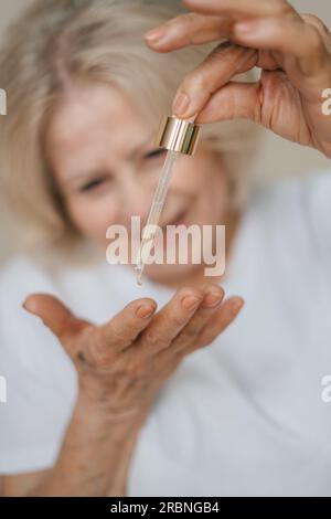 Ein anonymes Weibchen, das Hyaluronsäure auf ihre Hand aufträgt. Stockfoto