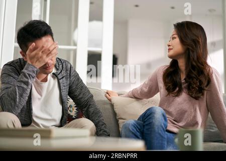 Ein junges asiatisches Paar, das zu Hause auf dem Familientisch sitzt und sich durch seine Eheprobleme quatscht Stockfoto