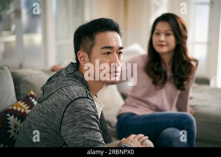 Ein junges asiatisches Paar, das zu Hause auf dem Familientisch sitzt und sich durch seine Eheprobleme quatscht Stockfoto