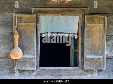 Ein Fenster mit Spitzenvorhang und Kürbis in einem alten Holzhaus im Dorf Krapje. Lonjsko Polje Naturpark, Kroatien. Stockfoto