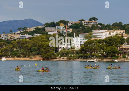 Eine Gruppe von Kanufahrern, die entlang der Küste von Alcanada, Alcudia, segeln. Mallorca, Balearen, Spanien. Stockfoto