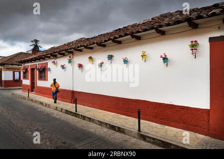 Einheimische Frau geht entlang einer bunt dekorierten Hausfassade, San Cristóbal de las Casas, Central Highlands (Sierra Madre de Chiapas), Mexiko, Nord A. Stockfoto